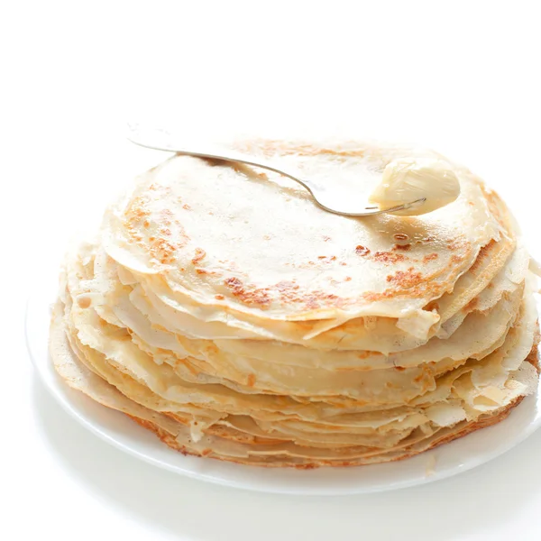 Viele Pfannkuchen mit Butter auf weißem Hintergrund — Stockfoto