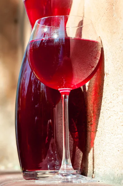 Copa de vino tinto casero con jarra sobre fondo de pared de piedra — Foto de Stock