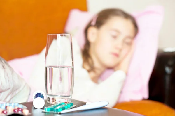 Leki i szklankę wody na chore dziecko śpiące. — Zdjęcie stockowe