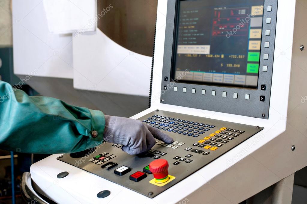 Worker hands on the control panel of a cnc programmable machine.