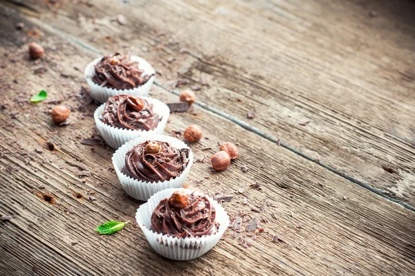 Rangée de cupcakes au chocolat avec des noisettes sur le dessus. Backgrou en bois — Photo