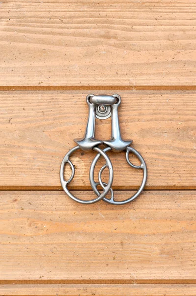 Steel horse snaffle-bit hanging on wooden background. — Stockfoto