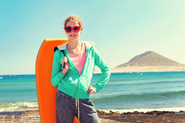 Teenage cheerful girl standing with surfboard on Atlantic ocean coast — Stock Photo, Image