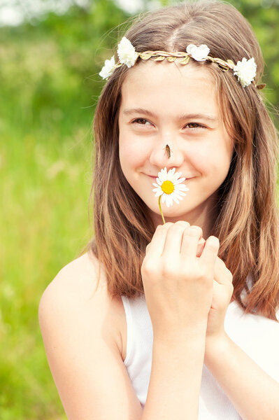 Summer is coming. Girl with butterfly on nose smelling camomile