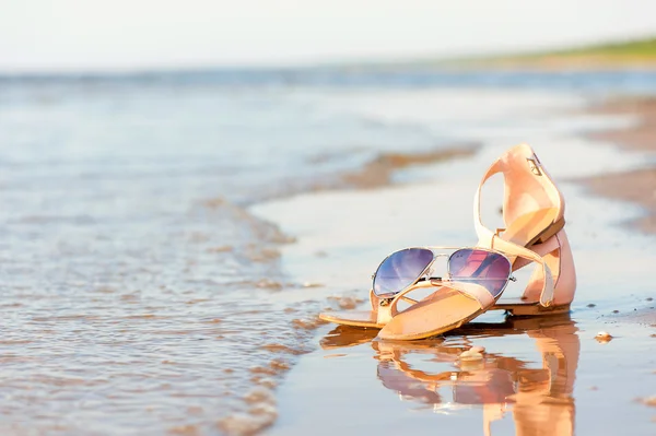 Fashionable women sandals and sunglasses on summer sandy wet coa — Stock Photo, Image