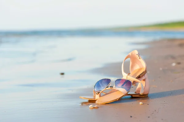 Fashionable women sandals and sunglasses on summer sandy wet coa — ストック写真