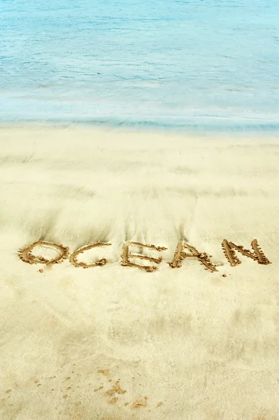 Word handwritten in wet sand on Atlantic ocean shore — Stock Fotó