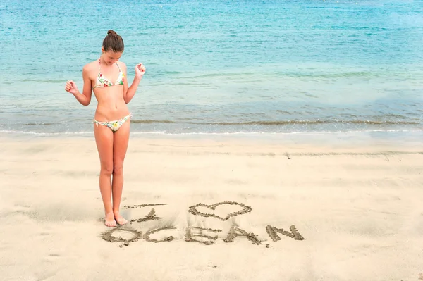 Молодая девушка-подросток с я люблю океан сообщение на песке — стоковое фото