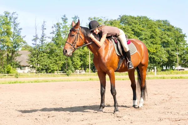 Fröhliche junge Teenager-Reiterin umarmt das Pferd — Stockfoto