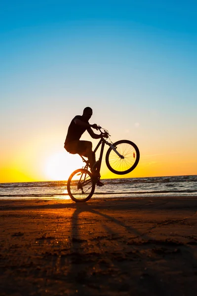 Hombre ciclista silueta en el cielo azul y multicolor puesta de sol espalda — Foto de Stock