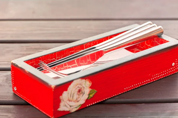 Metallisch glänzende Gabeln und Messer in roter Holzkiste. — Stockfoto