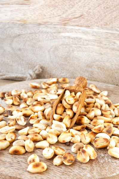 Heap of roasted peeled dry peanuts on wooden plank. Closeup. — Stock Photo, Image