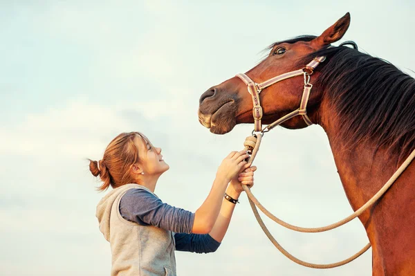 Young cheerful teenage girl calming big spirit chestnut horse. — Stock fotografie