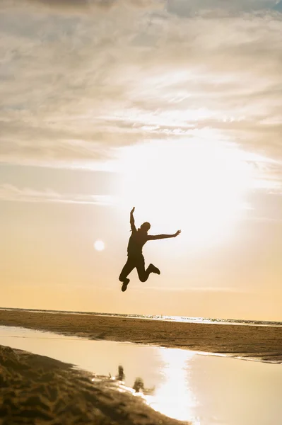 Junges springendes Mädchen Silhouette im Sonnenstrahl am Strand Sonnenuntergang. — Stockfoto