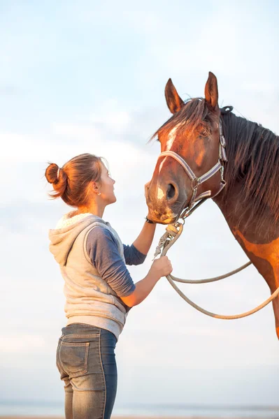 Junges fröhliches Teenager-Mädchen streichelt braune Pferdenase. Außenbereich — Stockfoto