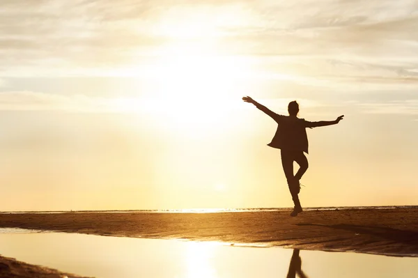 Happy girl silhouette dansant dans les rayons de soleil au coucher du soleil sur t — Photo