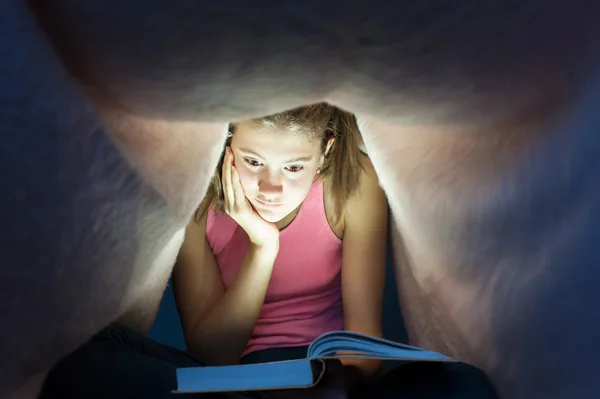 Genç kız battaniye ve enrapt okuma b ilginç altında gizleme — Stok fotoğraf