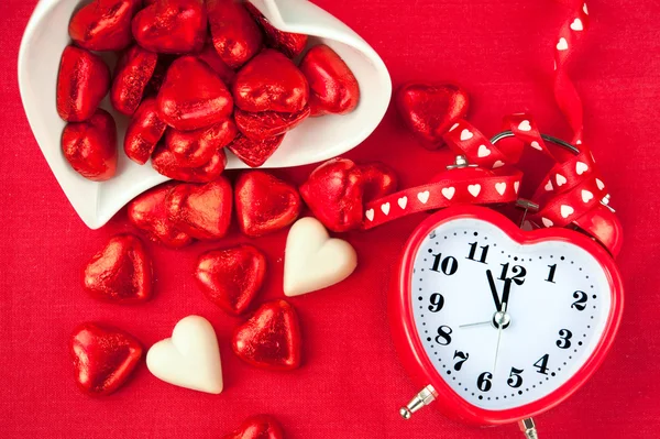 Está na hora do doce amor. Relógio em forma de coração vermelho com chocolates — Fotografia de Stock