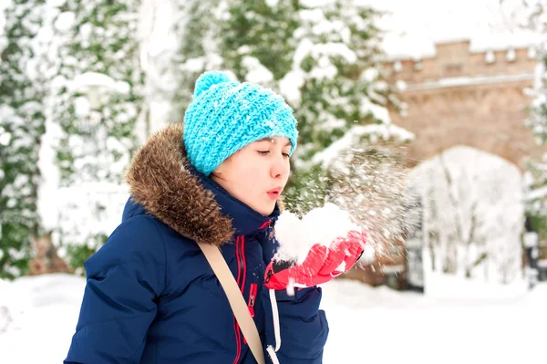 Genç neşeli genç kız yumuşak kar yığını üzerinde üfleme — Stok fotoğraf