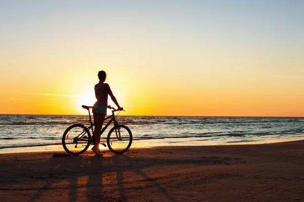 Bir anı yakalamak. Sportif kadın bisikletçi günbatımı backgr — Stok fotoğraf