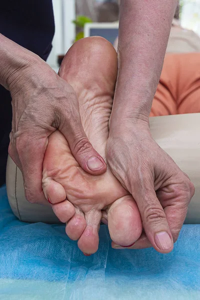 Masör ayak masajı yapıyor. Kendi elleriyle, ayak ve bacağa masaj yapıyor..
