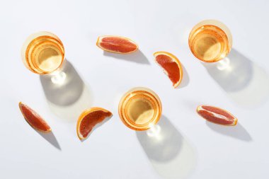 Beyaz zemin üzerinde portakal dilimleri olan birkaç bardak su..