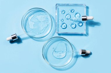 Damlalar ve değişik şekillerde hiyalüronik asit ile farklı şekillerde, farklı şekillerde, mavi arka planda. Kozmetik konsepti