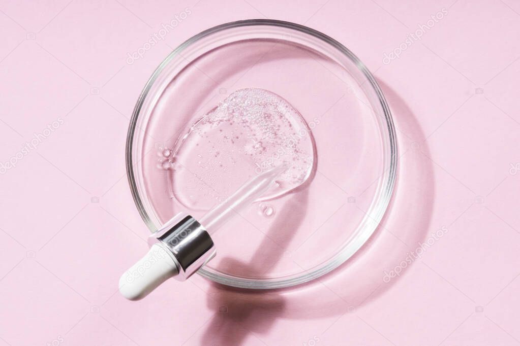 Pipette with a smear of hyaluronic acid on a round glass support, pink background. Cosmetics concept