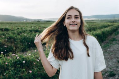 Güneşin batışında, dışarıda güzel, genç, doğal bir kız. Yazlık elbiseli narin sarışın yaz günbatımının doğasının ve özgürlüğünün tadını çıkarıyor.