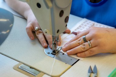 Dikiş, dikiş işi. Kadınların elleri dikiş makinesine dikilir.. 