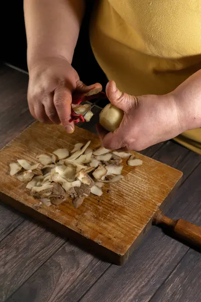 Peel a potato for mash on the wooden bottom