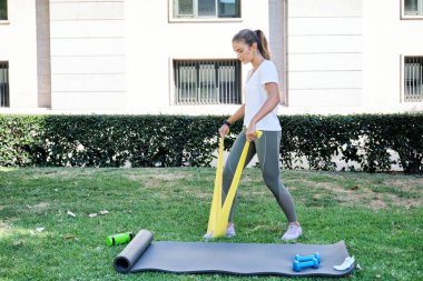 Beyaz bir kadın direniş grubuyla egzersiz yapıyor. Açık hava egzersiz konsepti.