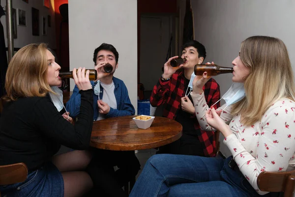 四个朋友带着面具在酒吧里喝啤酒 酒吧里的新常态 — 图库照片