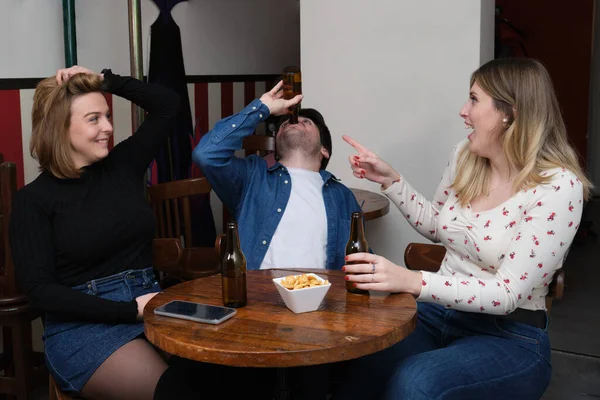 年轻人在酒吧里喝完了所有的啤酒 他的女朋友惊讶地看着他 友谊概念 — 图库照片