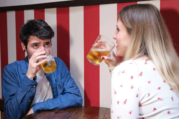 两个朋友在酒吧喝啤酒 背景上的红白条纹墙 — 图库照片