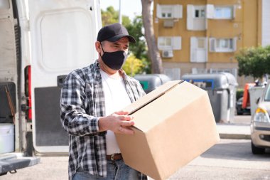 Karavanının önünde elinde bir paketle bekleyen son sınıf bir teslimatçı. Karantina, hastalık salgını, koronavirüs covid-19 salgını altında teslimat hizmeti.