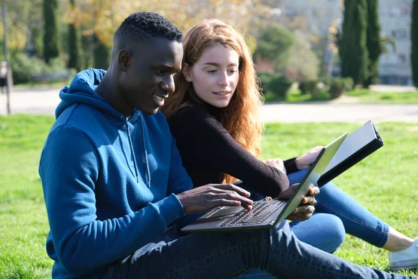 아프리카 남성과 코카서스 여성이 공원에서 노트북과 태블릿으로 일하고 있습니다 인종인 — 스톡 사진