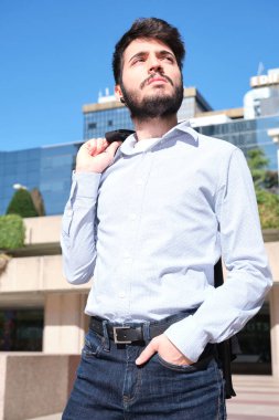 Genç iş adamı portresi arka planda binalara bakıyor. Bir şehrin kentsel caddesinde iş adamı.