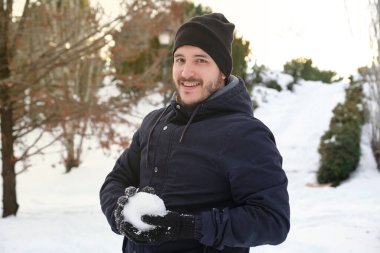 Madrid, İspanya 'da Filomena kar fırtınası sırasında elinde kartopu olan genç bir beyaz adam. Kış aktiviteleri.