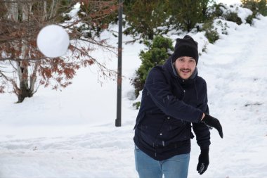 İspanya, Madrid 'de Filomena kar fırtınası sırasında parkta kar topu atan genç beyaz bir adam. Kış aktiviteleri.