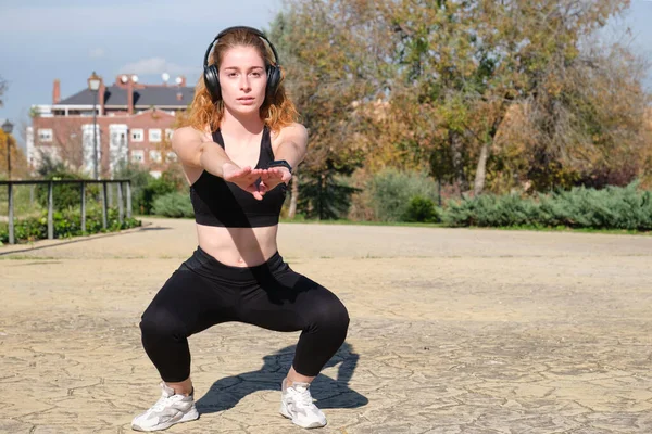 Rödhårig Kaukasisk Kvinna Med Hörlurar Som Knäböjer Fitness Och Sport — Stockfoto