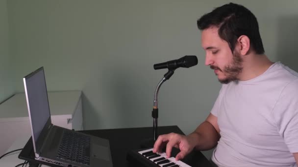 一位男性博主 你的导师 在家里录制了一段视频 弹奏了一架电子钢琴 音乐家 钢琴师 手提电脑上的白屏 — 图库视频影像
