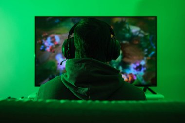 Kulaklık takan tanınmamış bir oyuncu, televizyondan video oyunları oynuyor. Yeşil ışık biçimi.