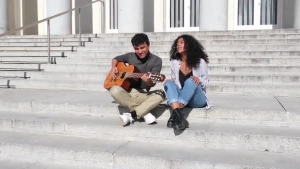 若いラテン系のカップルがギターを演奏し 階段に座って歌っている 千年世代 — ストック動画