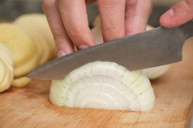 Soğan doğrayan insan ellerine yakın çekim. İçerik hazırlık konsepti.