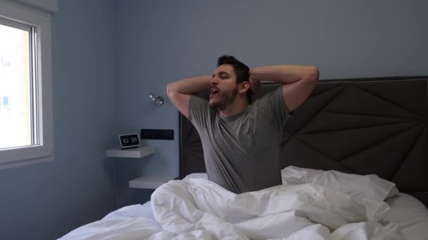 眠った後 若いラテン系の男性がベッドの中であくびとストレッチ スローモーション 4Kビデオ — ストック動画