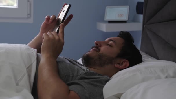 Junger Mann Mit Smartphone Bett Der Einen Digitalen Assistenten Bittet — Stockvideo