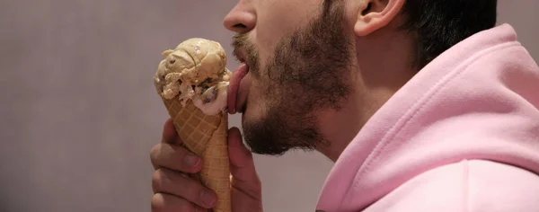 Dondurma külahını yalayan tanınmamış bir adam. Panoramik fotoğraf pankartı.