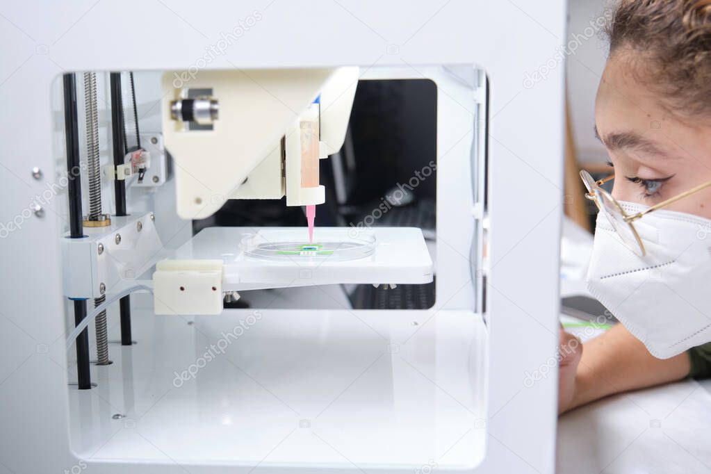 Researcher adjusting a 3D bioprinter to 3D print cells onto an electrode. Biomaterials, tissue engineering concepts.