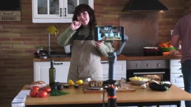 Genç bir kadın kameraya guacamole pişirmeyi ve yemek kanalı için akıllı telefonuyla video kaydetmeyi anlatıyor. İçerik yaratan ve etkileyen.